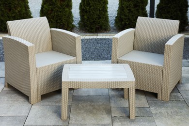 Photo of Comfortable armchairs and coffee table outdoors. Beautiful rattan garden furniture