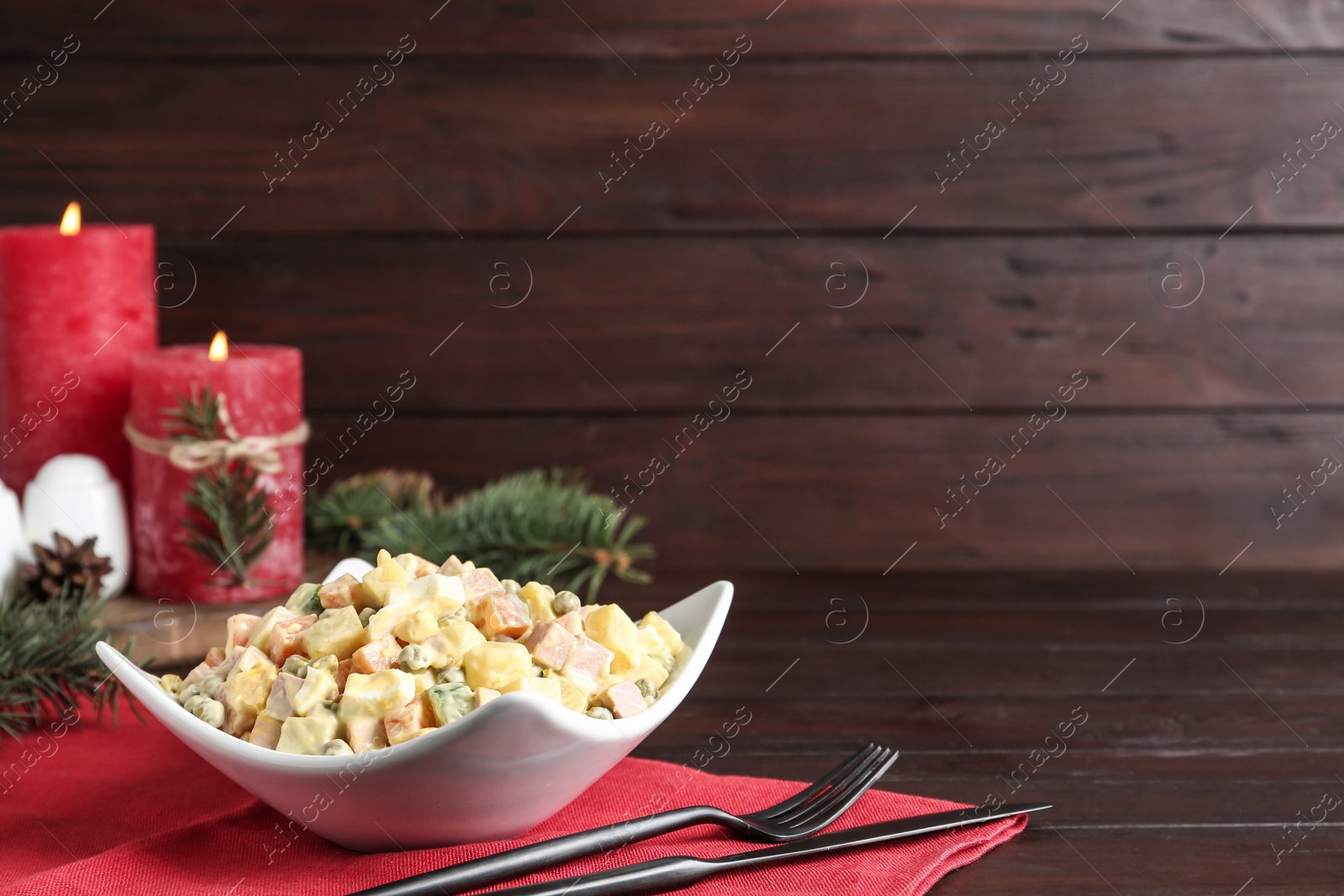 Photo of Traditional russian salad Olivier served on wooden table, space for text