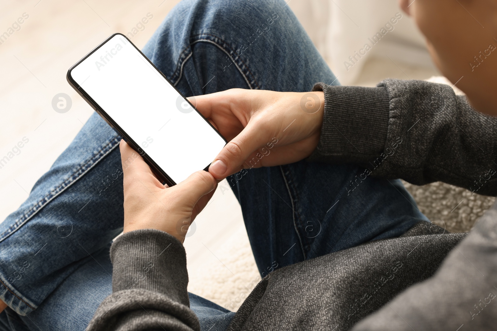 Photo of Man using smartphone with blank screen indoors, closeup. Mockup for design