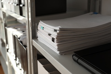 Stack of documents with paper clips on shelf in office