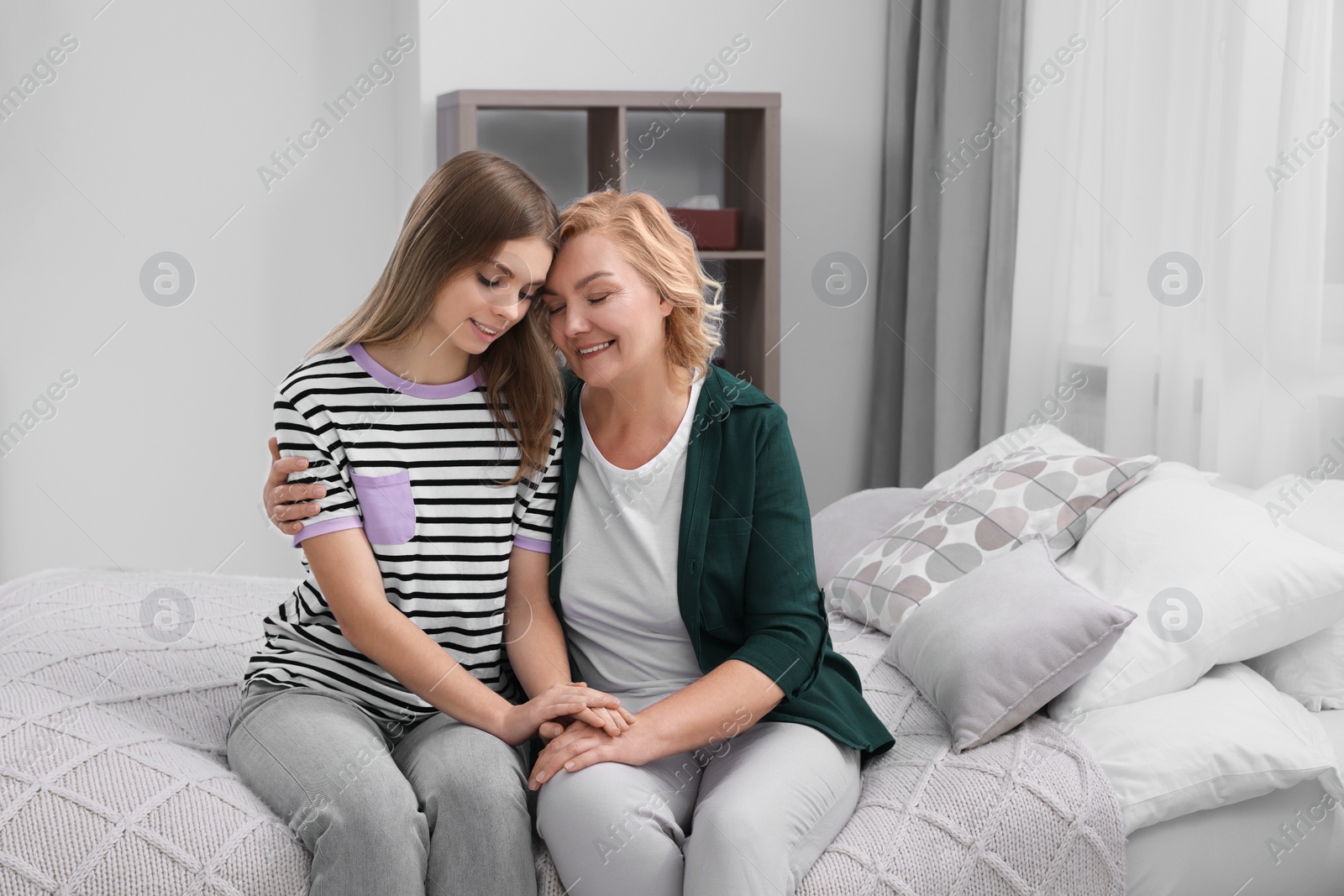 Photo of Young woman with her mom on bed at home. Happy Mother's Day