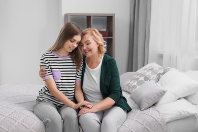 Photo of Young woman with her mom on bed at home. Happy Mother's Day