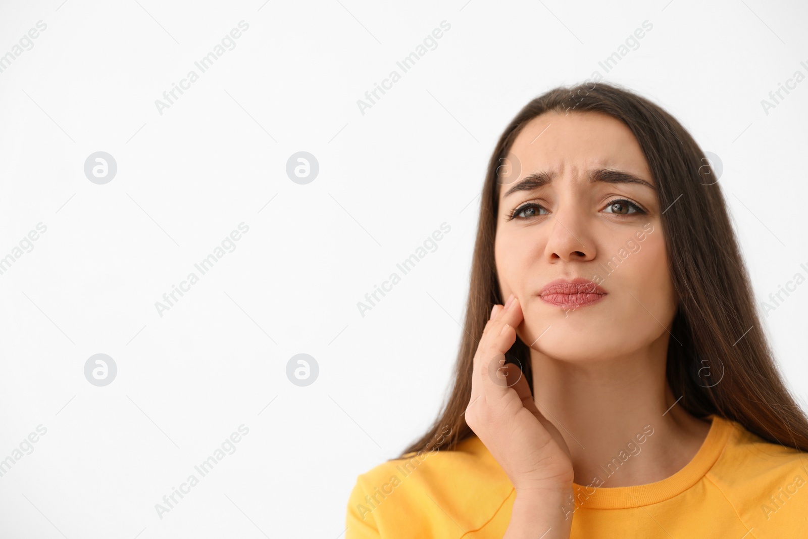 Photo of Young woman suffering from strong tooth pain on light background, space for text