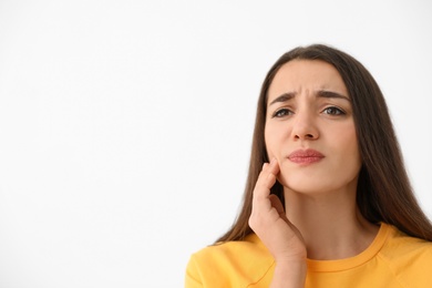 Young woman suffering from strong tooth pain on light background, space for text