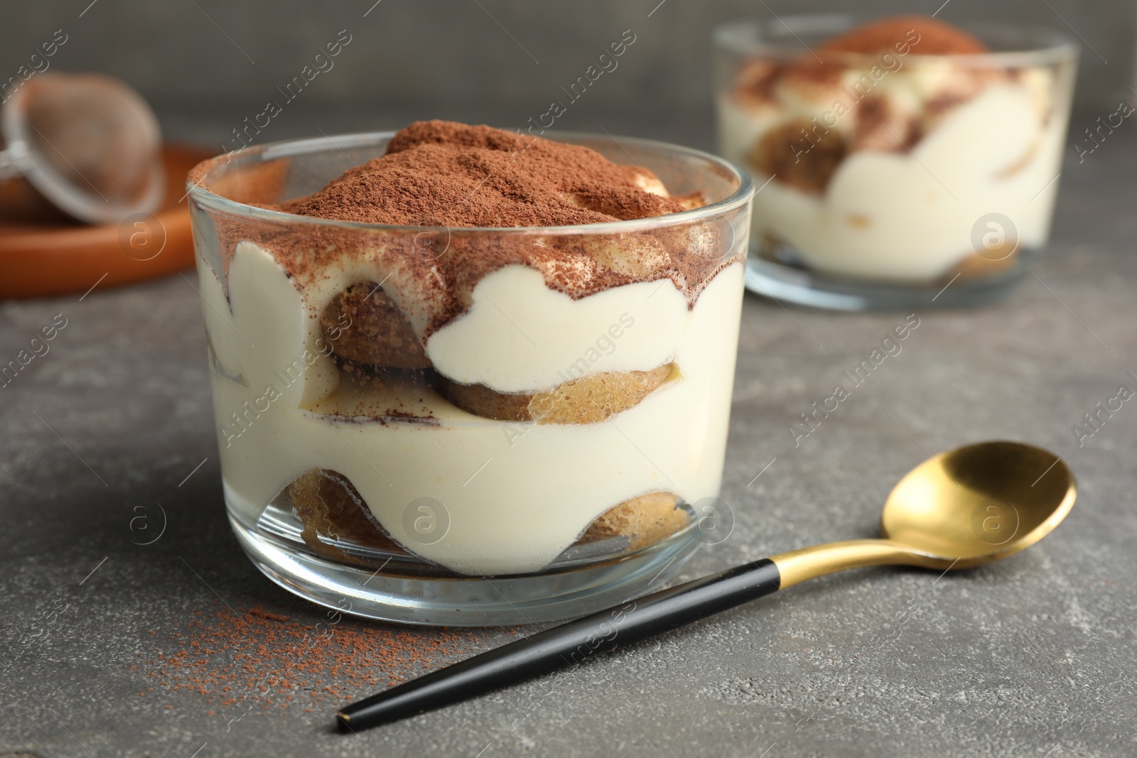 Photo of Delicious tiramisu in glass on grey table