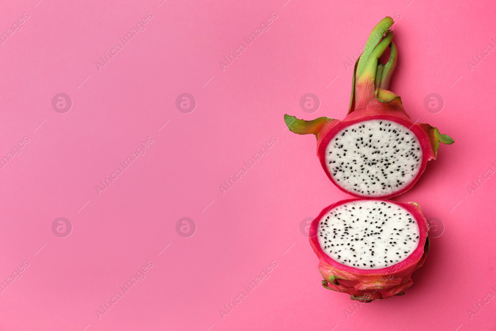 Photo of Halves of delicious ripe dragon fruit (pitahaya) on pink background, top view. Space for text