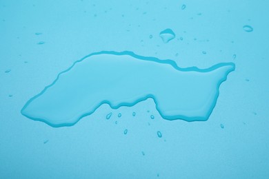 Puddle of water on light blue background, above view