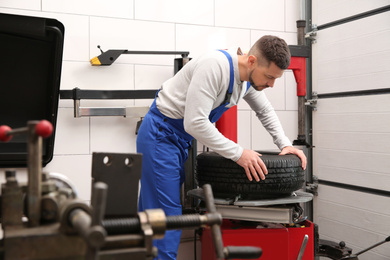 Mechanic working with tire fitting machine at car service