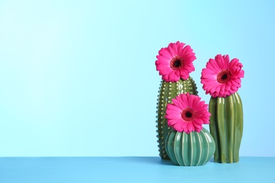 Photo of Decorative cacti and flowers on table against color background, space for text. International Women's Day