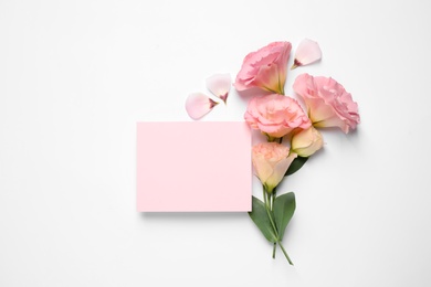 Photo of Beautiful Eustoma flowers and blank card on white background, flat lay. Space for text
