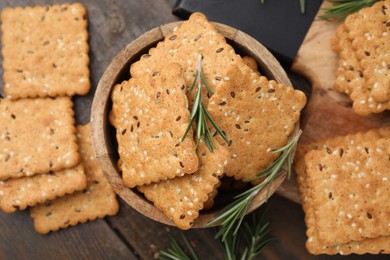 Photo of Cereal crackers with flax, sesame seeds and rosemary on wooden table, flat lay