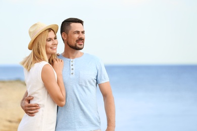 Happy romantic couple spending time together on beach, space for text