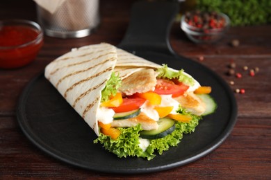 Photo of Delicious shawarma with chicken meat and vegetables  on wooden table, closeup
