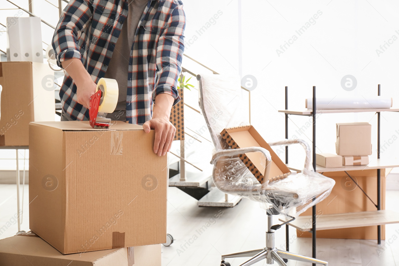 Photo of Young man packing moving box indoors, closeup