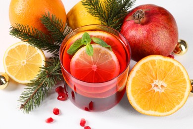 Photo of Christmas Sangria drink in glass, fir branches and fruits on white background, closeup