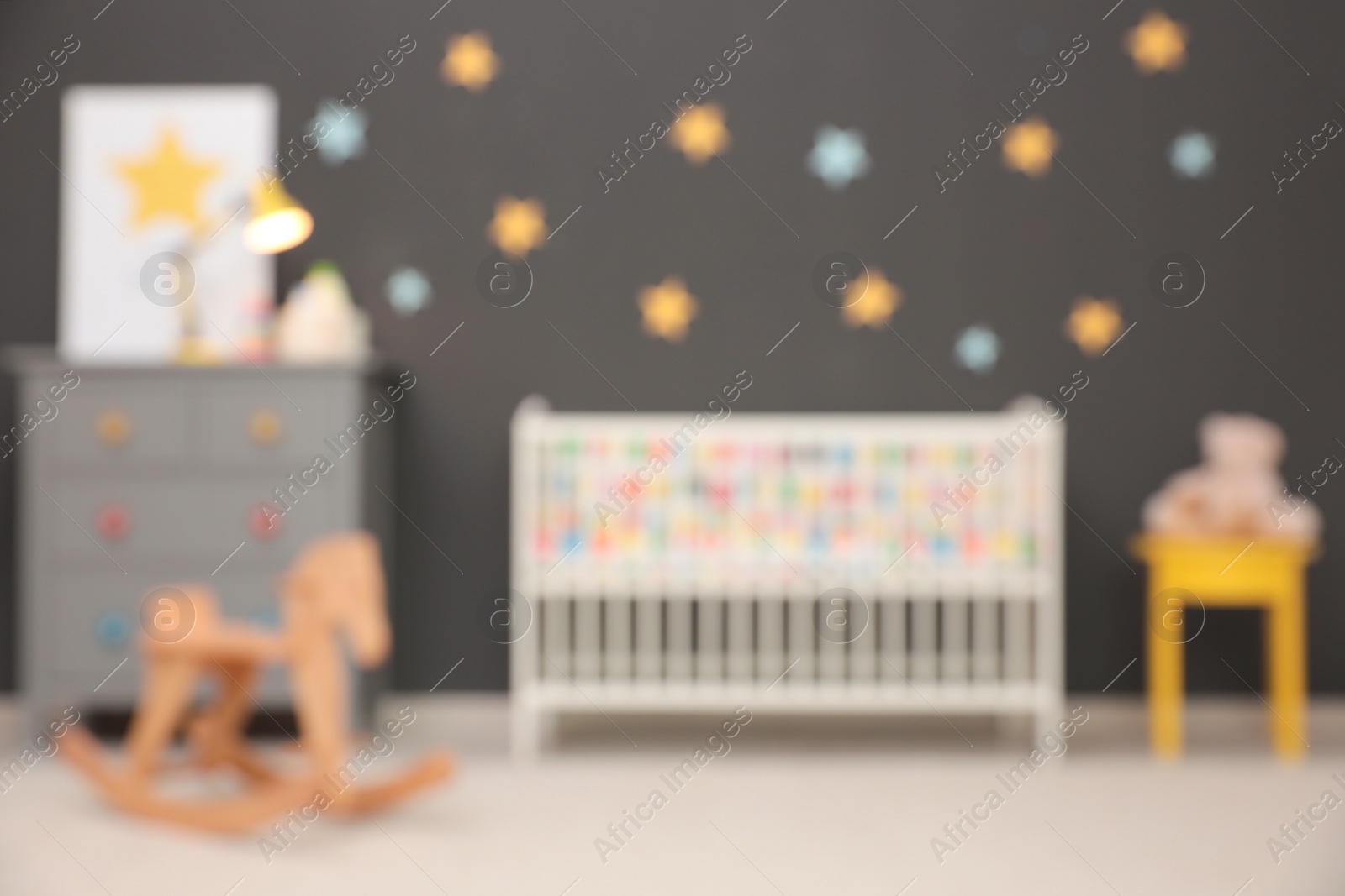 Photo of Blurred view of cute baby room interior with modern crib and rocking horse