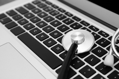 Photo of Modern laptop and stethoscope, closeup. Technical support concept