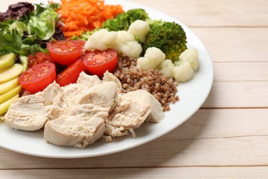 Photo of Balanced diet and healthy foods. Plate with different delicious products on light wooden table, closeup