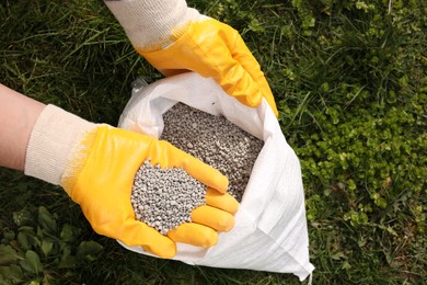 Photo of Woman with fertilizer on green grass outdoors, top view