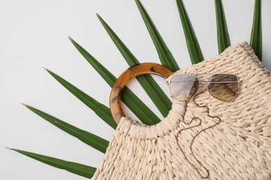 Stylish straw bag and sunglasses on white background, top view. Summer accessories