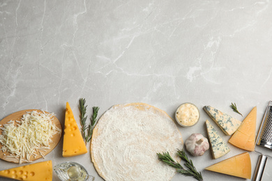 Photo of Flat lay composition with dough and fresh ingredients on grey marble table, space for text. Pizza recipe