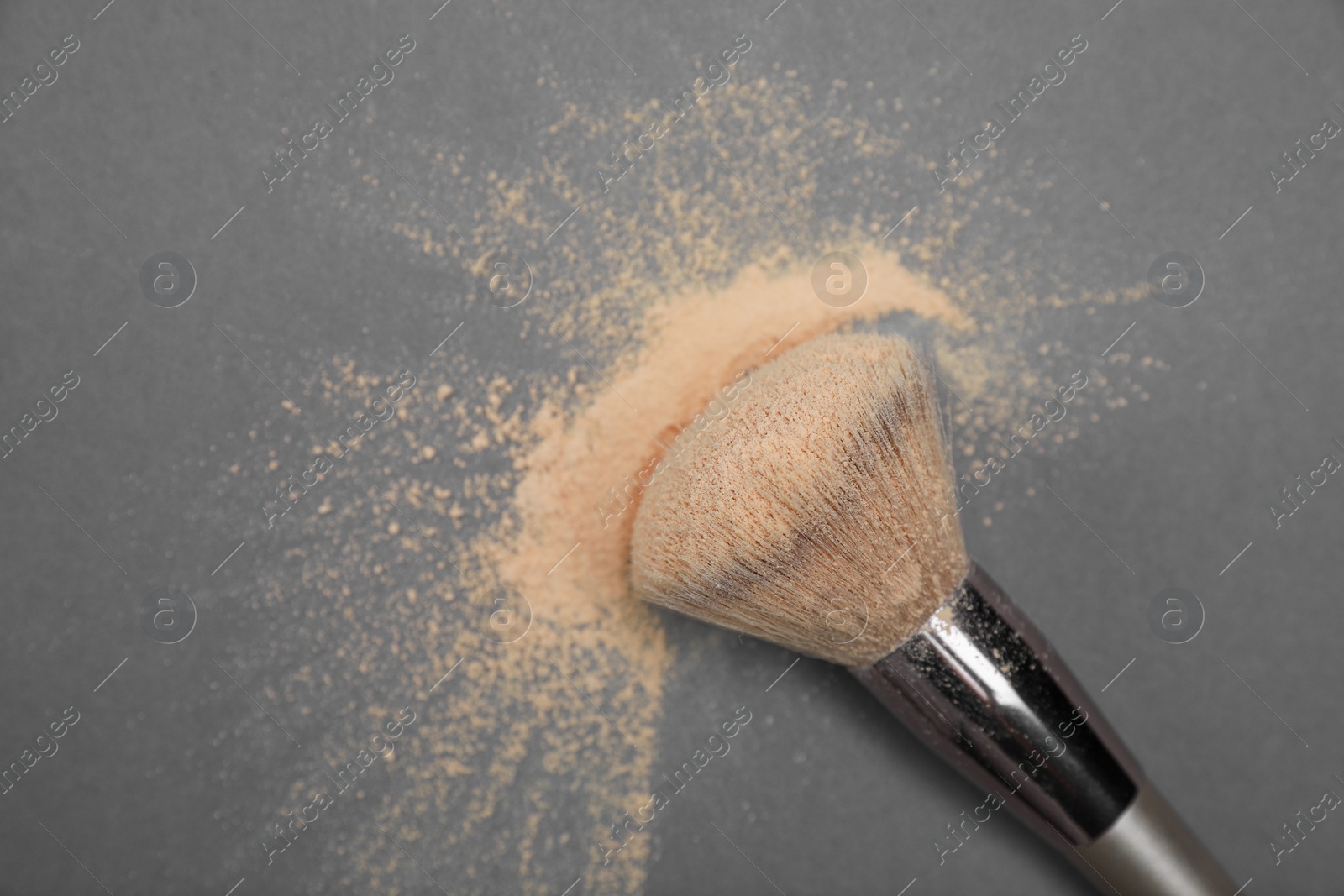 Photo of Loose face powder and makeup brush on grey background, flat lay