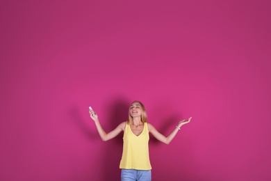 Photo of Young woman operating air conditioner with remote control on color background