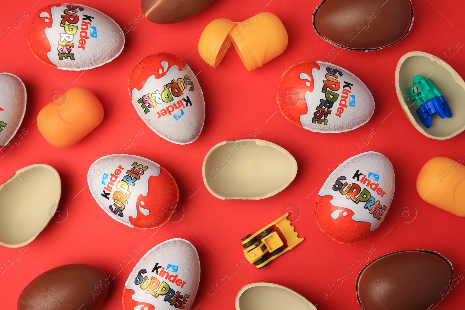 Photo of Sveti Vlas, Bulgaria - June 29, 2023: Kinder Surprise Eggs, plastic capsules and toys on red background, flat lay