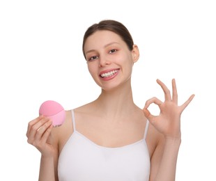 Photo of Washing face. Young woman with cleansing brush showing OK gesture on white background