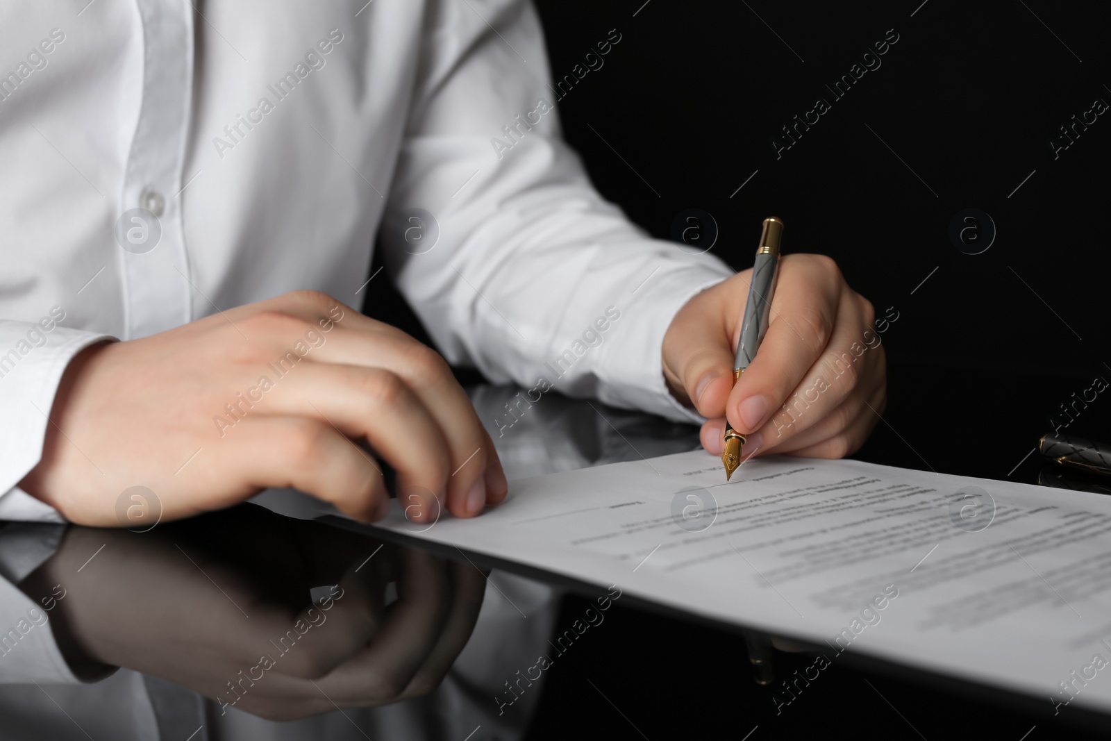 Photo of Notary signing document at black table, closeup