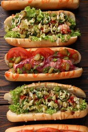 Different tasty hot dogs on wooden table, above view