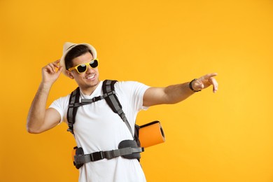 Male tourist with travel backpack on yellow background