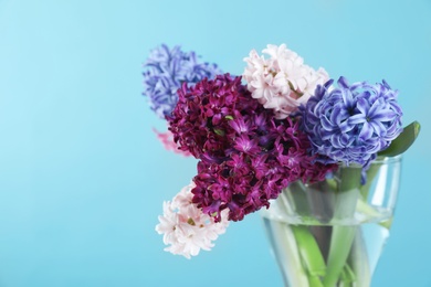 Beautiful hyacinths in glass vase on color background, space for text. Spring flowers