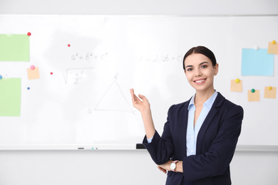 Photo of Young teacher near whiteboard in modern classroom. Space for text