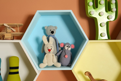 Photo of Hexagon shaped shelves with toys on orange wall. Interior design
