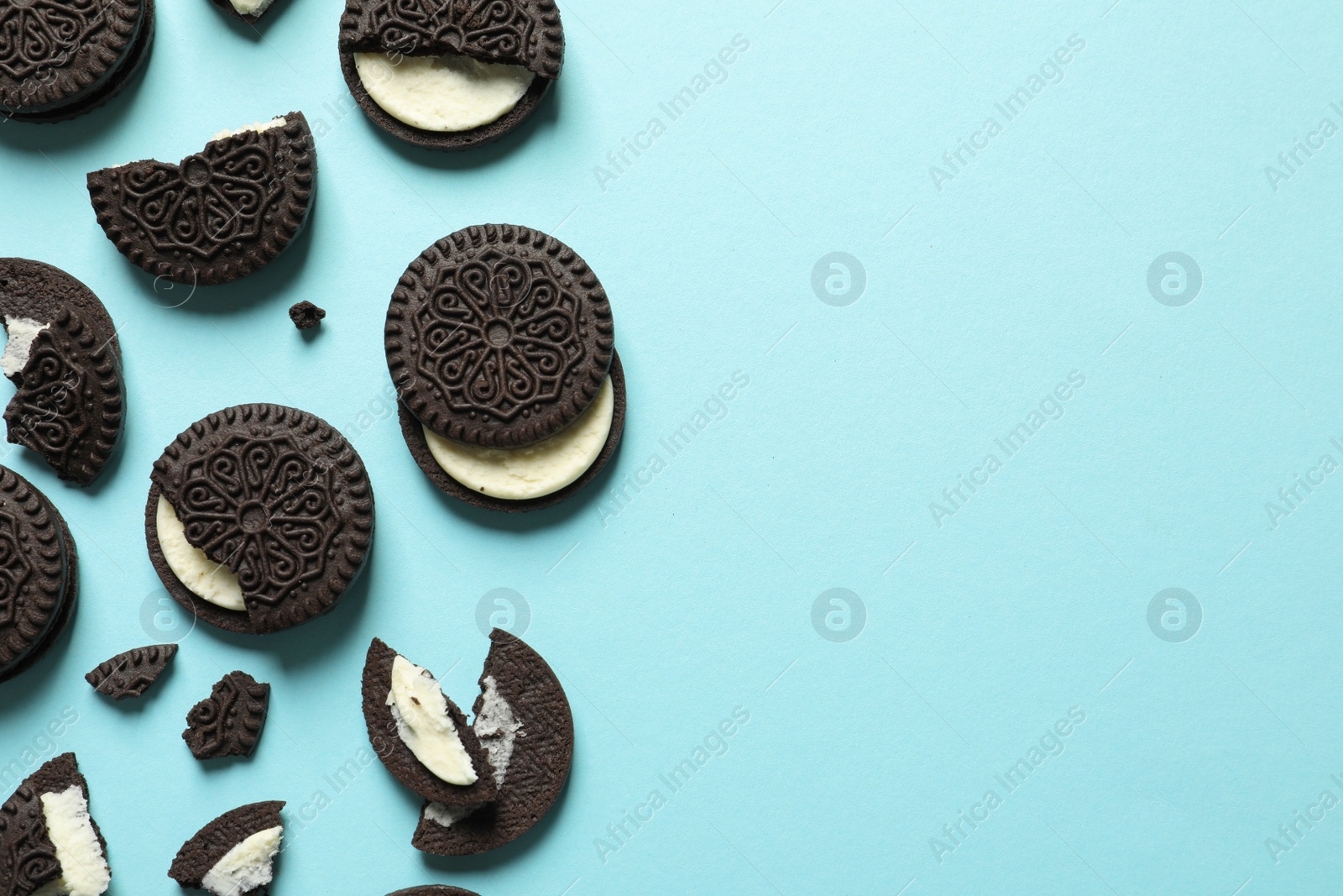 Photo of Tasty chocolate cookies with cream on color background, flat lay. Space for text