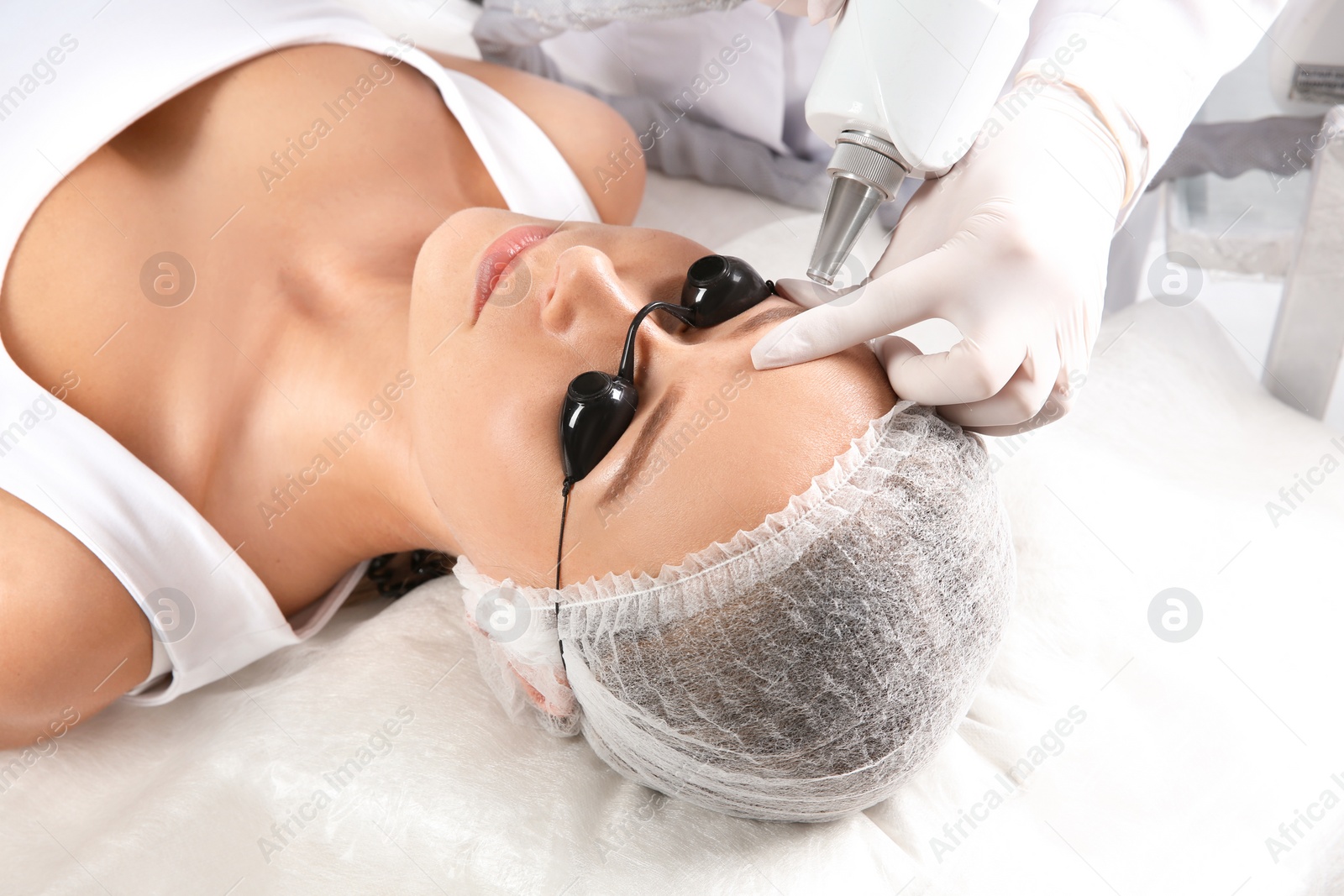 Photo of Young woman undergoing laser removal of permanent makeup in salon. Eyebrow correction