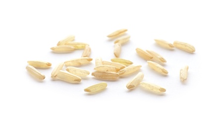 Photo of Scattered grains of brown rice on white background