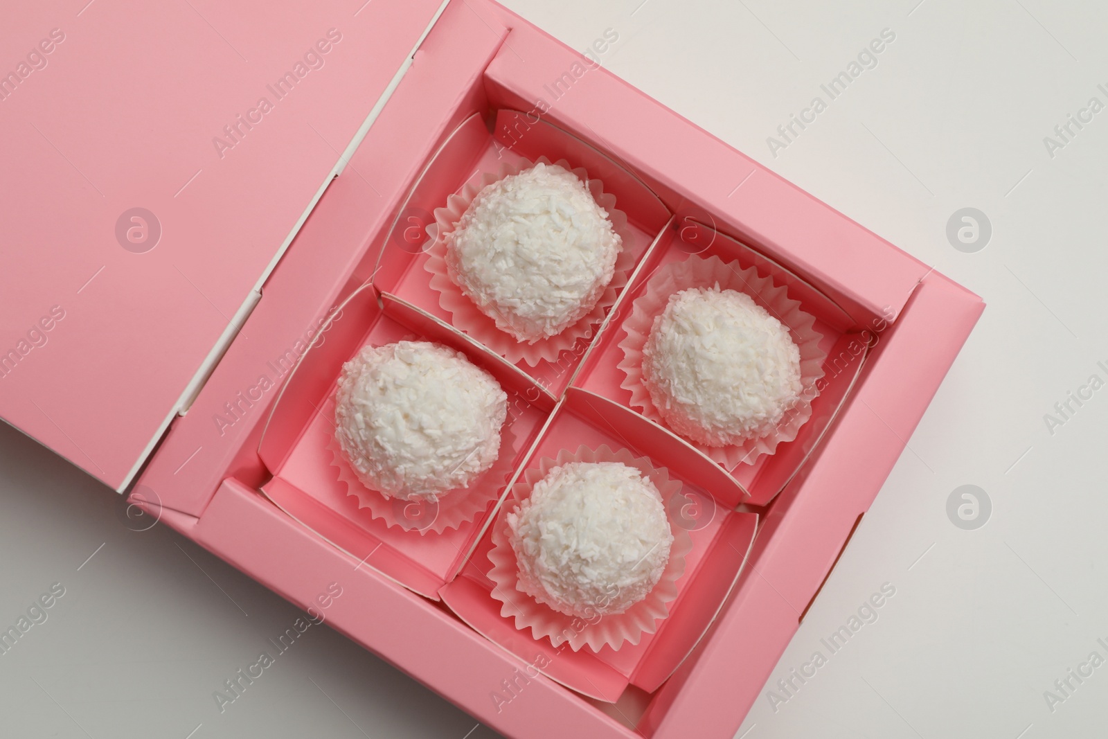 Photo of Delicious candies in pink box on light grey background, top view