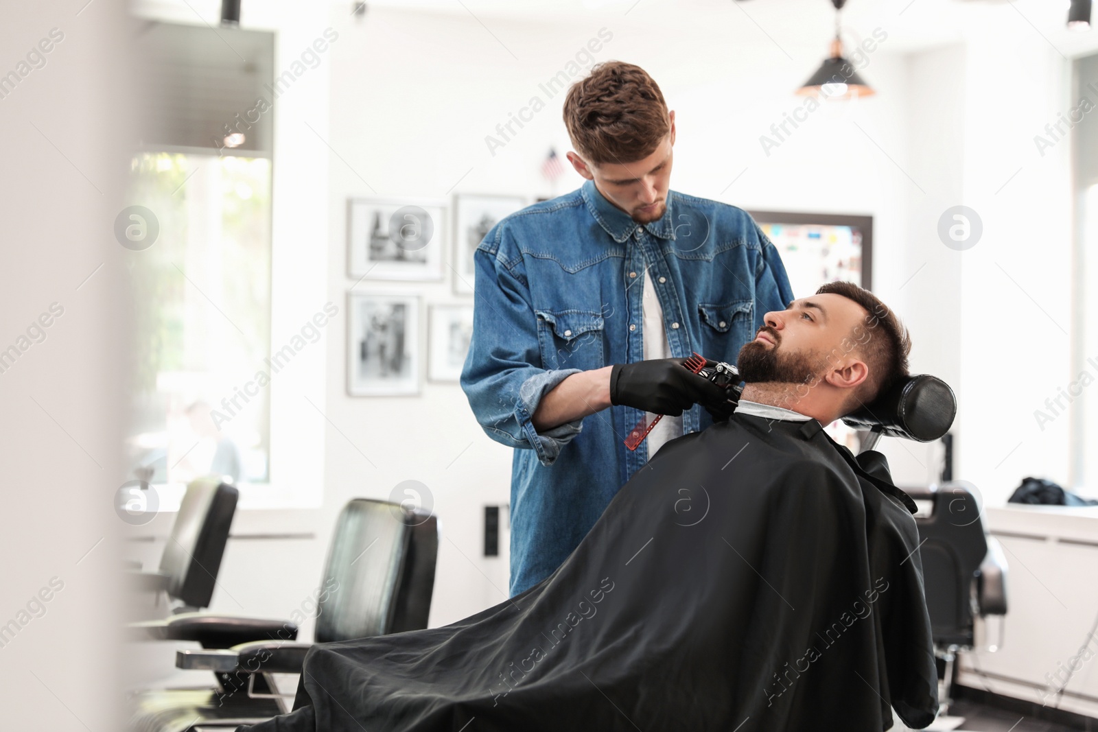 Photo of Professional barber working with client in hairdressing salon. Hipster fashion