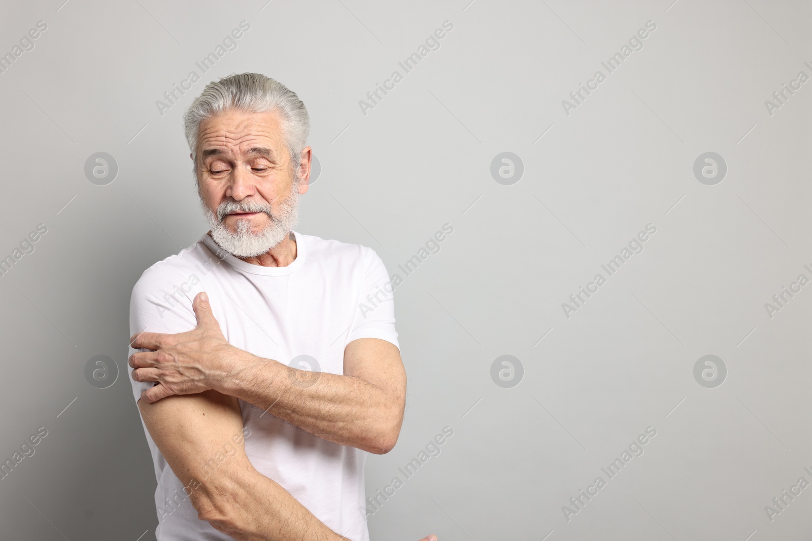 Photo of Arthritis symptoms. Man suffering from pain in shoulder on gray background, space for text