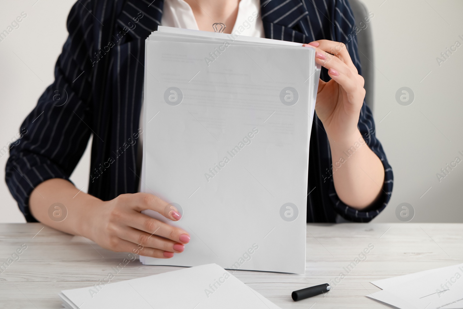 Photo of Woman stacking documents at white wooden table in office, closeup