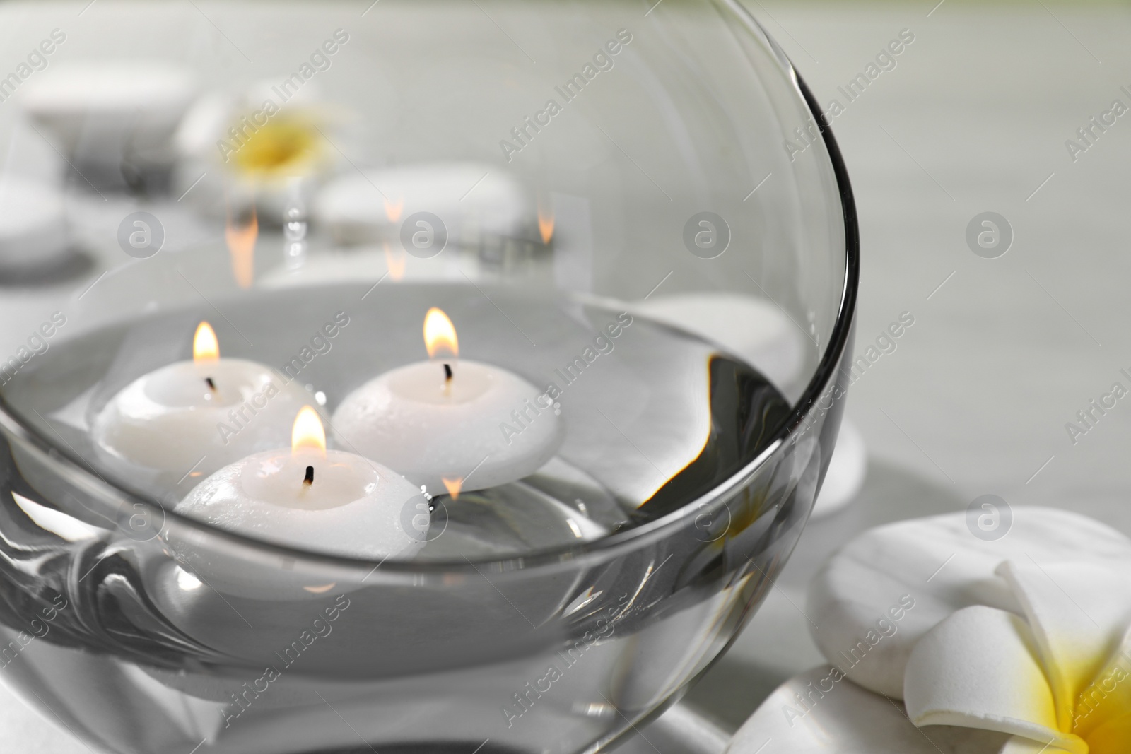 Photo of Vase of water with burning candles and spa stones on grey table, space for text