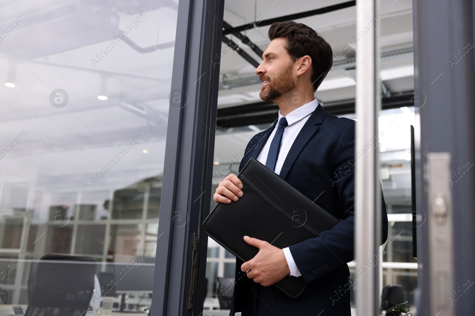 Photo of Male real estate agent with leather portfolio outside office