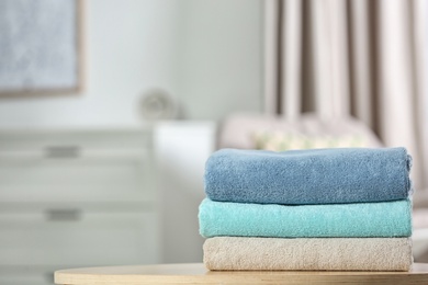 Photo of Stack of folded clean soft towels on table indoors. Space for text