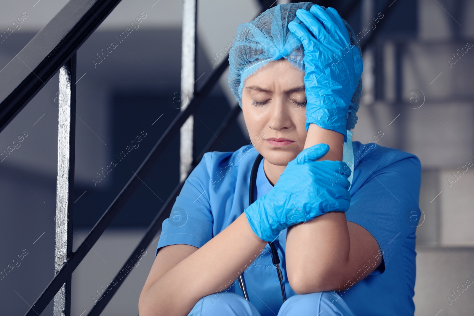 Photo of Exhausted doctor sitting on stairs in hospital