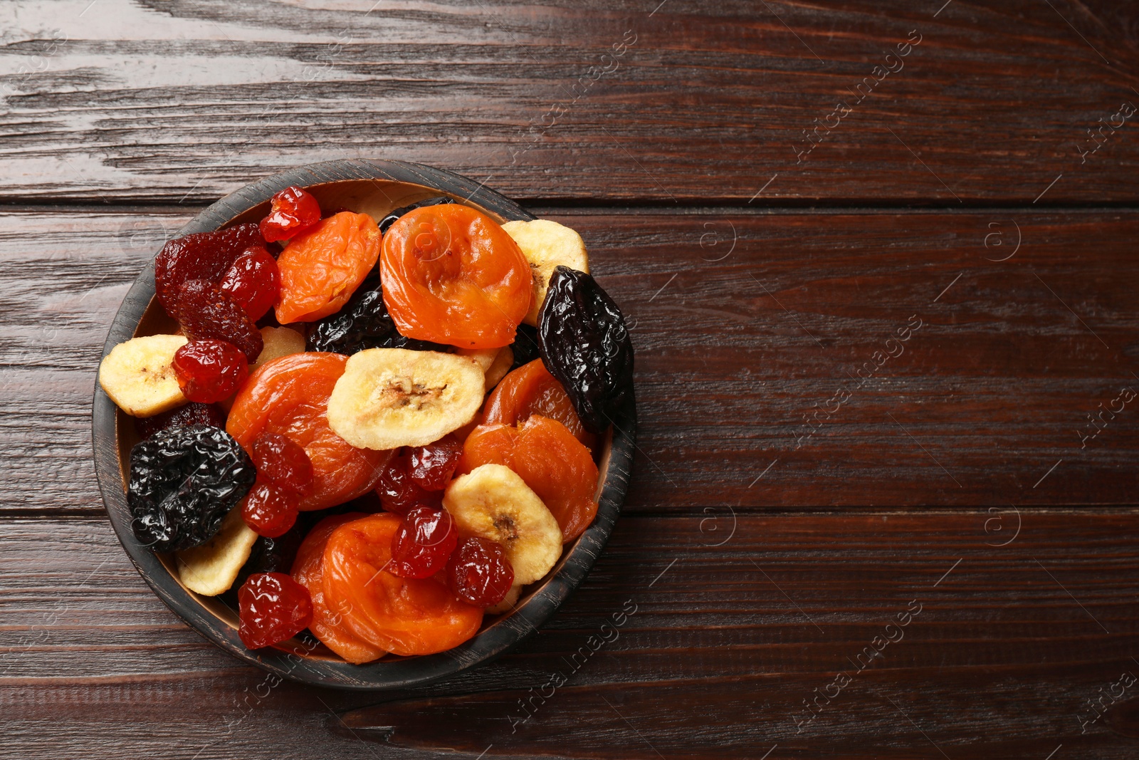 Photo of Mix of delicious dried fruits on wooden table, top view. Space for text