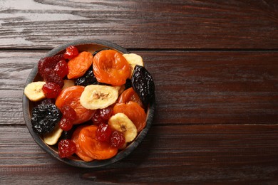 Photo of Mix of delicious dried fruits on wooden table, top view. Space for text