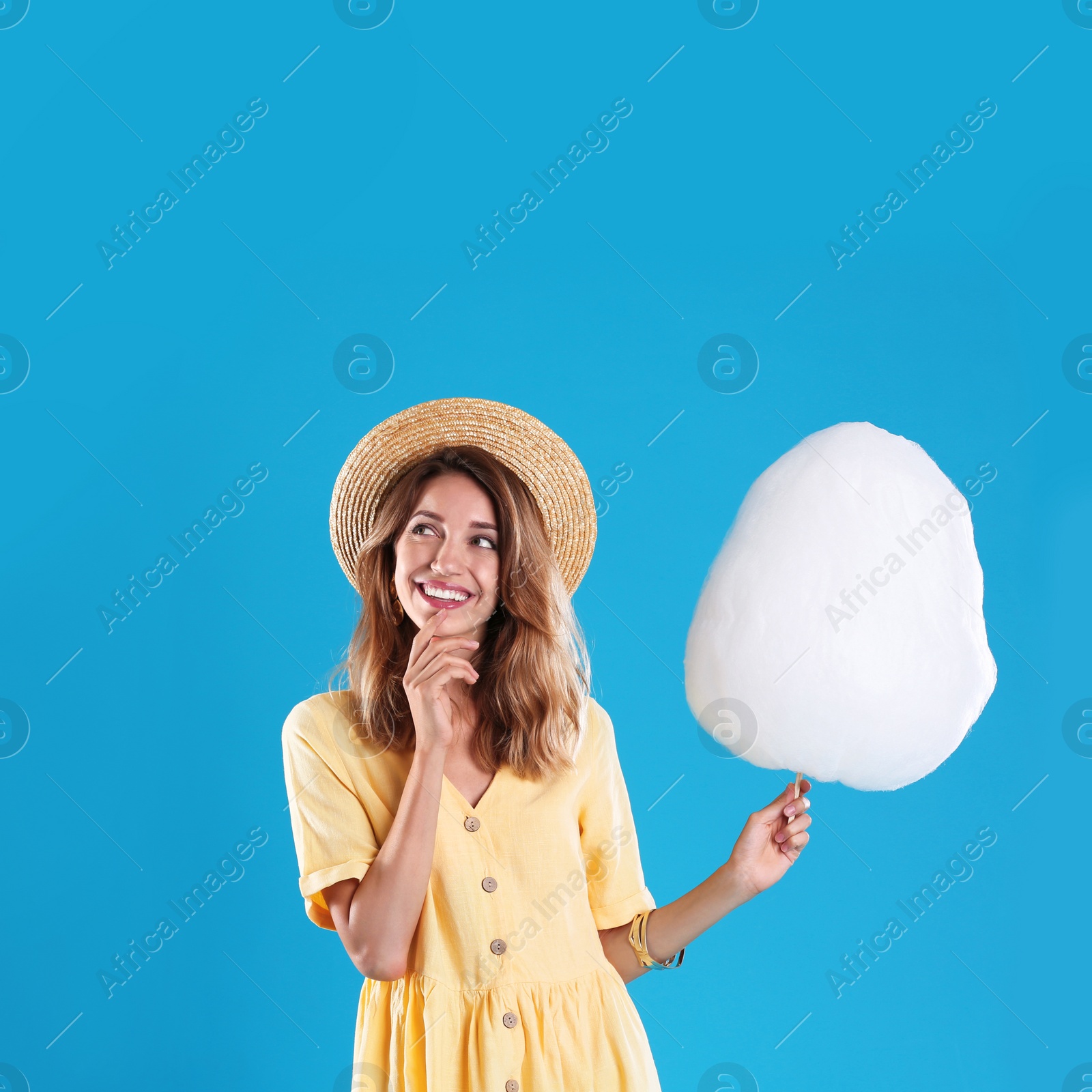 Photo of Happy young woman with cotton candy on blue background