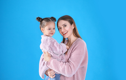 Young mother and little daughter on blue background